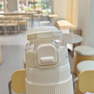 Close-up of the secure safety lock and flip-top lid mechanism on white vacuum water bottle