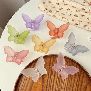 Flat lay of colorful matte oversized bow hair clips on a wooden tray with a floral cloth