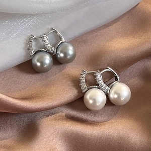Detail of luxury grey and white pearl earrings with zircon accents on satin fabric