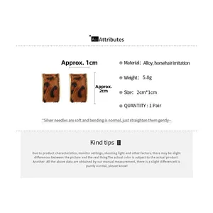 Macro detail of vintage leopard print C-shaped earrings with alloy and horsehair texture