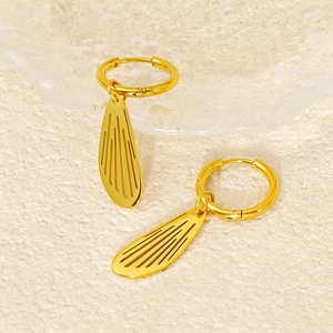 Polished gold hollow wing earrings with hoop closure on elegant beige textured background