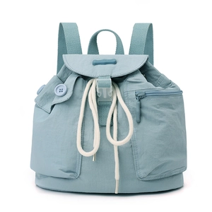 Detail of light blue nylon backpack with drawstring closure and brand logo on flap