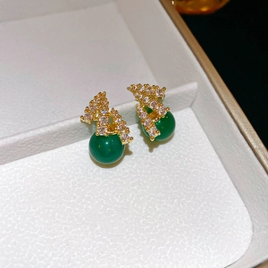 Dettaglio di orecchini di zircone verde smeraldo con metallo dorato e micro-pavé di pietre