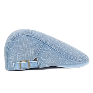 Detailed texture of light blue denim flat cap with bronze metal adjustment buckle