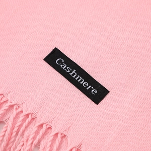 Detail of pink cashmere scarf showing soft fabric texture, fringe, and product label