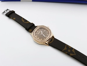 Detail of square rose gold watch case with crystal bezel and brown monogram strap