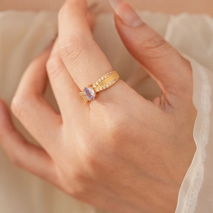 Nahaufnahme eines Goldrings mit ovalem lila Zirkonia und funkelnden Kristallakzenten