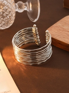 Detail of silver multi-layer wavy C-shaped open bangle on an elegant studio background