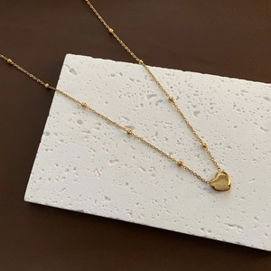 Close-up of golden heart pendant engraved with Real Love on a bead snake chain