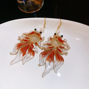 Detail of goldfish earrings with red enamel work and elegant white pearl accents