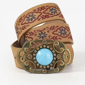 Close-up of vintage bronze belt buckle with turquoise stone and floral embroidery