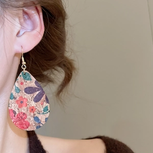 Detail of vintage teardrop leather earring with floral pattern on a female model
