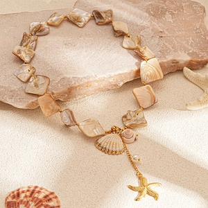 Detail of seashell necklace featuring mother-of-pearl charms and golden starfish pendant