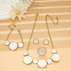 Flat lay of gold jewelry set with white marble drip oil necklace, bracelet and ring