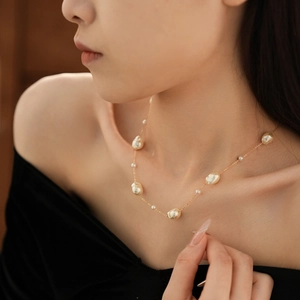 Detail of baroque pearl necklace on model showing irregular pearls and gold chain