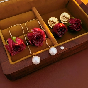Détail macro de boucles d'oreilles roses rouges avec perles et pièces en boîte en bois