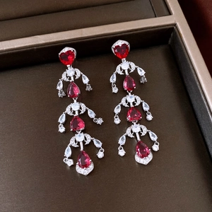 Detail of red heart zircon earrings with long tassels in a dark jewelry box