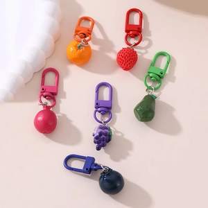 Detailed view of colorful resin fruit keychains including strawberry and avocado shapes