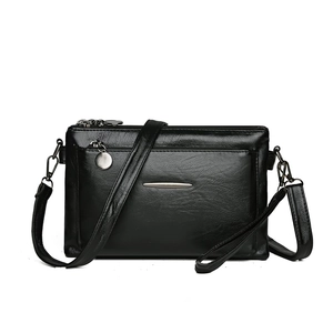 Minimalist black soft leather crossbody bag with multiple zippers and detachable strap