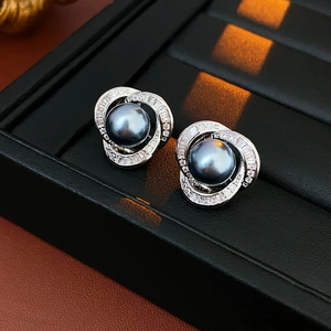 Dettaglio macro di orecchini con perle grigio scuro e pavé di zirconi in argento lucido