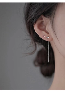 Close-up of silver S925 heart earrings and long tassel chain threader on ear