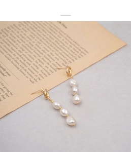 Detail view of French vintage knotted gold earrings with three baroque pearls on gray fabric