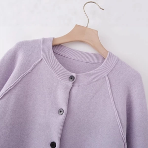 Lavender knit cardigan with round neck and black buttons on wooden hanger