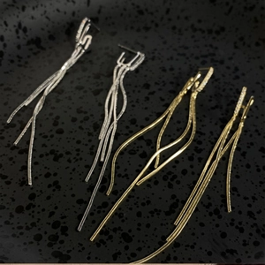 Elegant close-up detail of double tassel earrings with shimmering zirconia accents and silver needles