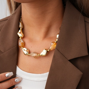 Detail of chunky irregular acrylic beads with amber texture and golden metal accents