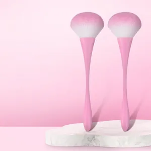 Close-up of two professional tapered makeup brushes with soft pink and white gradient bristles