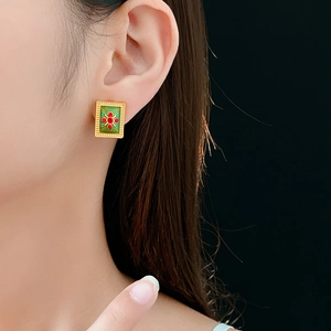 Detail of vintage square emerald green enamel earrings with red gemstone on model