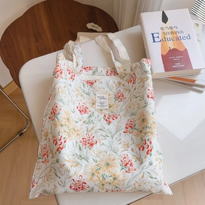 Gros plan détaillé d'un sac cabas en toile à fleurs avec des anses tissées blanches