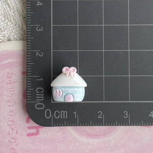 Macro detail of miniature 1.5cm resin house charm on a metric ruler for size reference