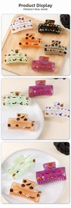 Close-up of Halloween square hair claws with pumpkin and ghost prints on a ceramic tray