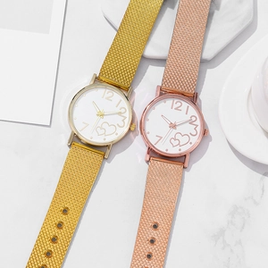 Detail of fashion women's watch with heart-patterned dial and mesh band on marble back