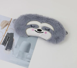 Detail of soft plush sloth sleep mask in grey and white on a minimalist white background