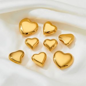 Minimalist golden heart stud earrings made of stainless steel on white silk fabric