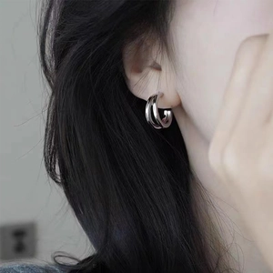 Close-up of minimalist interlocking silver hoop earrings on female model