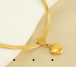 Detailed view of polished 18K gold heart charms on a sleek stainless steel snake chain