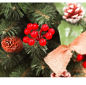 Close-up of red berries, pine cones, and burlap bow detail on mini Christmas tree