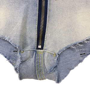 Makrodetail des Metallreißverschlusses und der Fransen an hellblauen Denim-Shorts