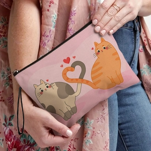 Pink fabric makeup bag with cartoon cat heart print held by a model in casual wear