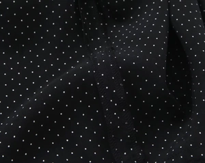 Detailopname van zwarte chiffon stof met witte stippen, fijne stiksels en zachte textuur