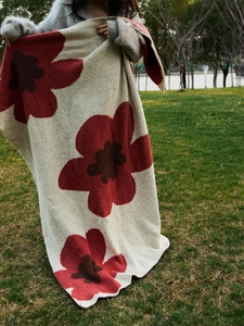 Detail of soft cream knit blanket with large red sunflowers in an outdoor setting