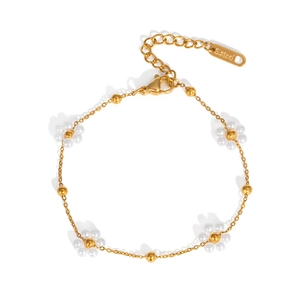 Détail du bracelet doré avec fleurs blanches et poinçon S.Steel sur le fermoir
