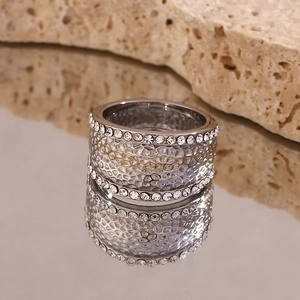Macro shot of silver textured ring with crystal edges on stone surface reflection