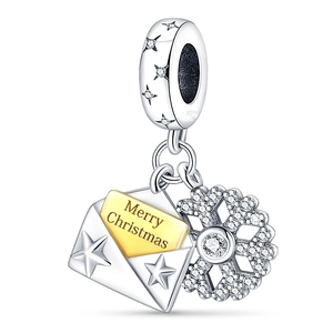 Macro shot of silver snowflake charm and golden Merry Christmas envelope pendant