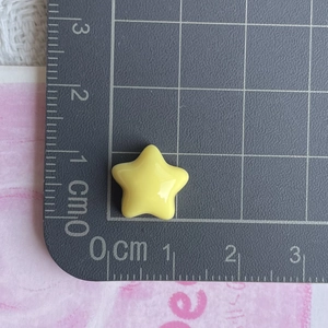 Close-up of yellow star resin accessory on grid mat measuring about 1.3 cm in width