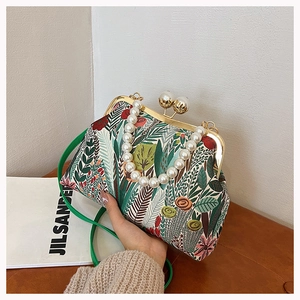 Detail der floralen Stofftasche mit Perlengriff und Metallverschluss in stilvoller Handaufnahme