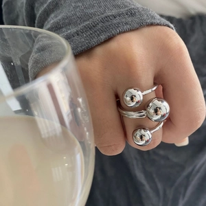 Close-up of three-ball silver brass ring on hand holding a glass cup for stylish look